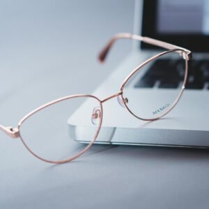 Close-up of stylish eyeglasses on a sleek laptop, symbolizing modern tech and productivity.