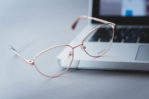 Close-up of stylish eyeglasses on a sleek laptop, symbolizing modern tech and productivity.