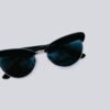 From above of trendy sunglasses with dark lenses and creative design placed on clear white background in modern light studio