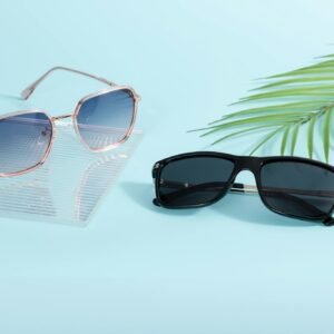 Two pairs of trendy sunglasses on a pastel surface with palm leaf decor.